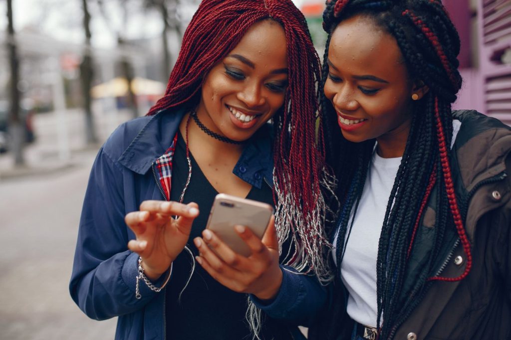 Two black women viewing a mobile device